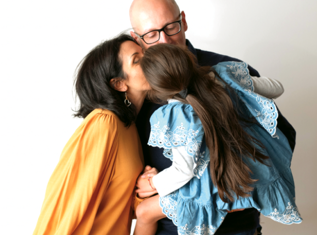 Famiglia di genitori e bambina si abbraccia affettuosamente