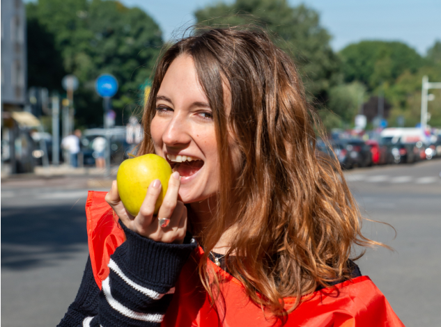 Ragazza sorridente morde una mela